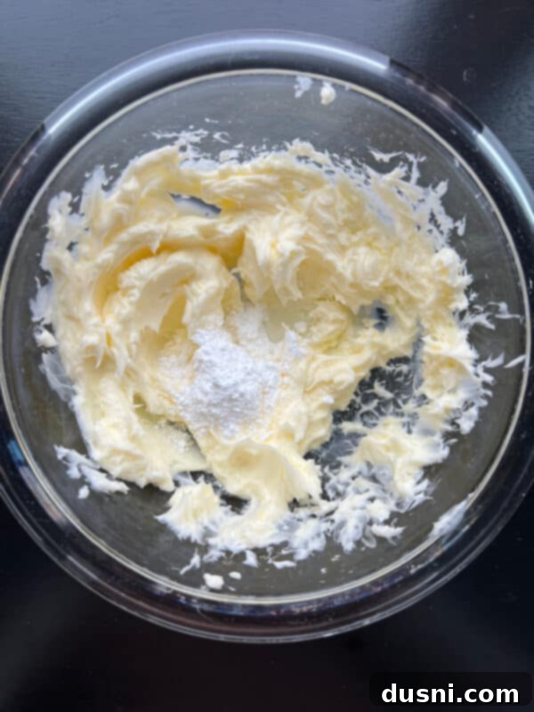 Cherry Cloud Spread 7 Adding almond extract and powdered sugar to creamed butter in a mixing bowl.