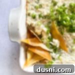 Savory Crab Rangoon Dip 16 Close up of Crab Rangoon Dip with wonton chips in a white baking dish.