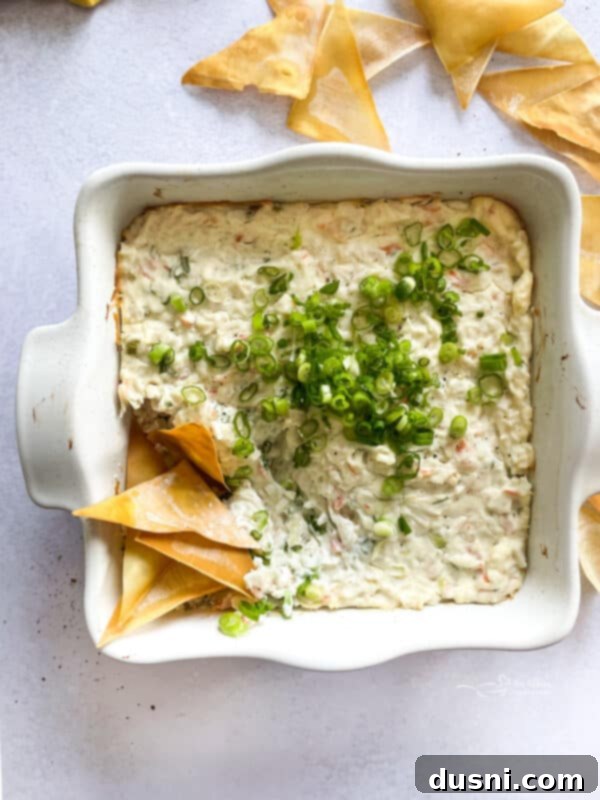 Savory Crab Rangoon Dip 3 A close-up of a warm, bubbly Crab Rangoon Dip in a white baking dish, ready to be served.