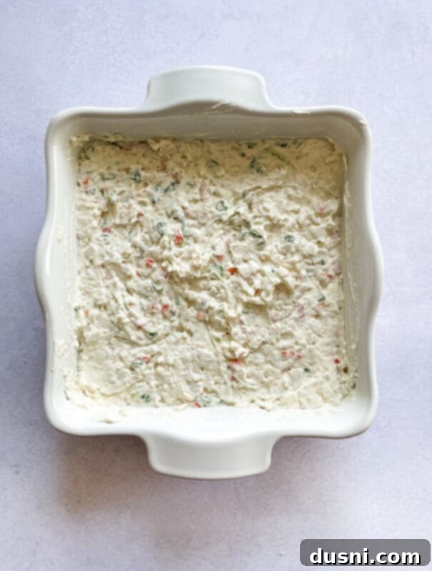 Savory Crab Rangoon Dip 8 Chopped imitation crab meat and green onions being folded into the creamy cheese mixture in a bowl.