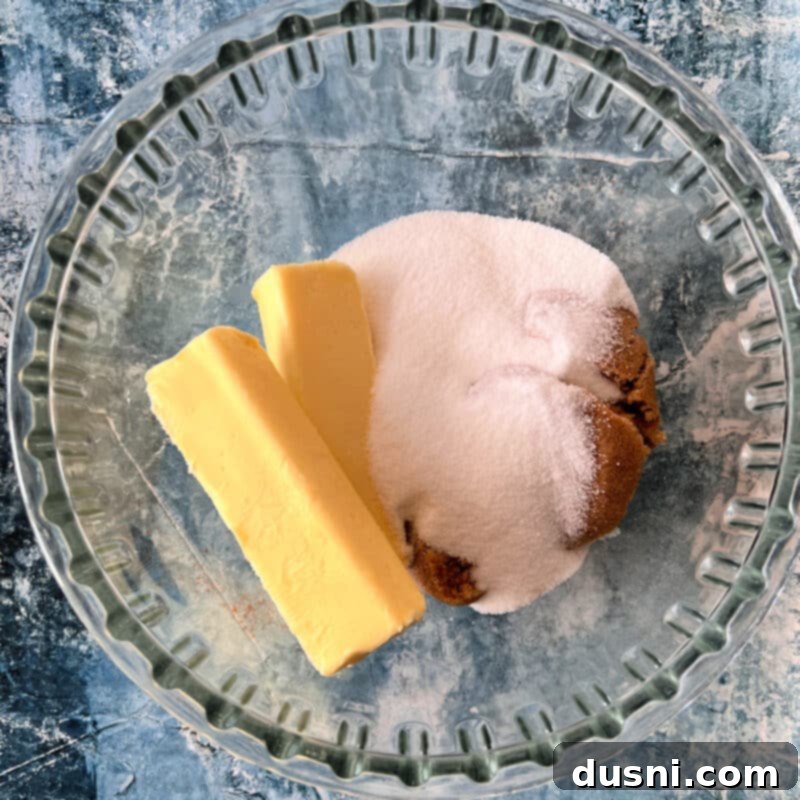 Creaming butter and sugars together in a mixing bowl with an electric mixer.