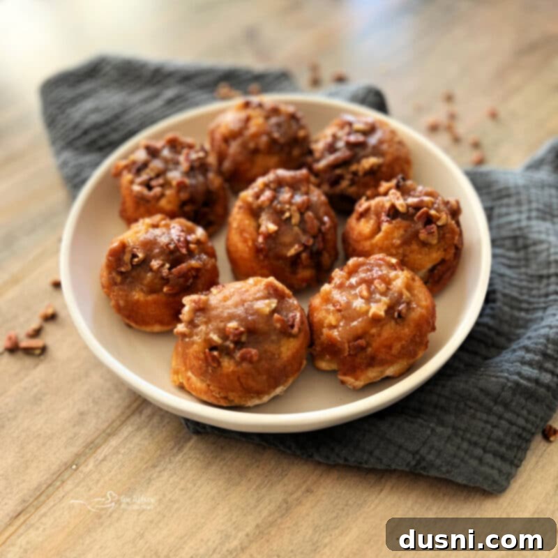 Banana Pecan Swirls 13 Overhead shot of freshly baked banana pecan sticky rolls cooling on a wire rack, with some rolls partially visible in a muffin tin in the background.