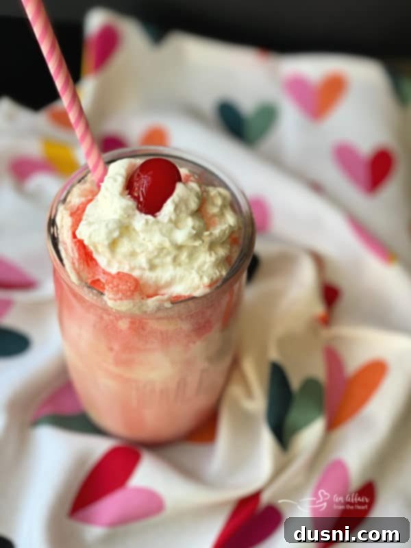 Sparkling Shirley Temple Float 3 Close-up of a Shirley Temple Float with layers of soda and ice cream, garnished with whipped cream and a cherry