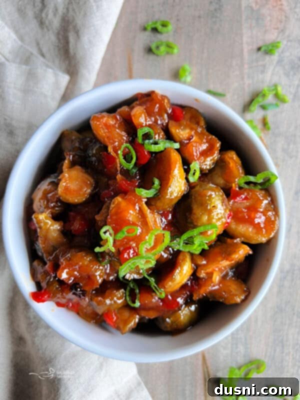 Sweet and Sour Brussels Sprouts in a serving bowl, garnished with green onions.