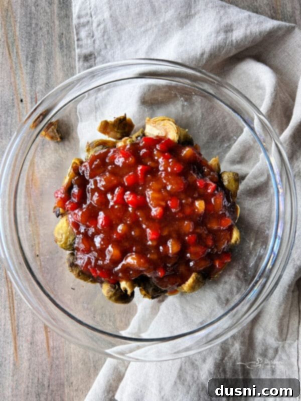Pouring sweet and sour sauce over air fried Brussels sprouts