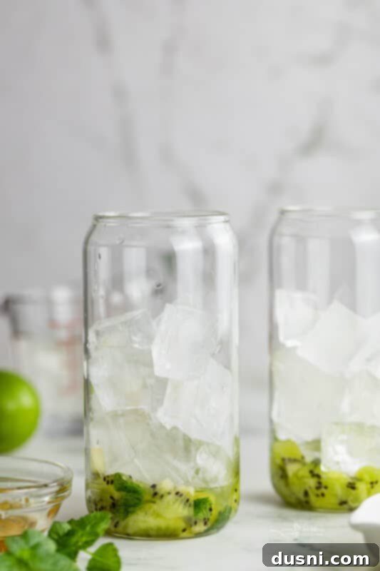 Vibrant Kiwi Mojito 7 Step four: A tall glass being filled with ice cubes after muddling.