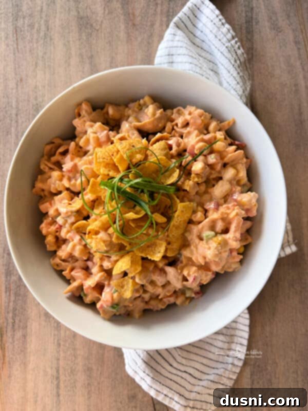 Loaded Frito Corn Salad 2 A large white bowl filled with Frito Corn Salad, garnished with whole Frito chips on top.