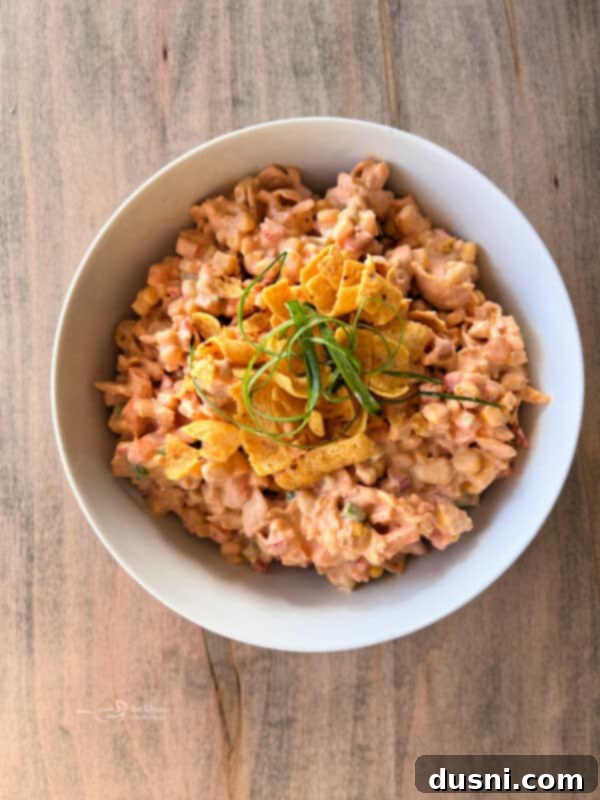 Loaded Frito Corn Salad 11 A serving of Frito Corn Salad in a bowl, with a fork, ready to be eaten.