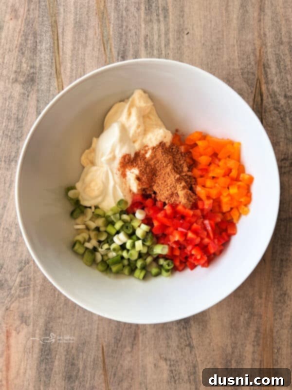 Loaded Frito Corn Salad 5 Step 1: Mixing mayonnaise, sour cream, taco seasoning, bell peppers, and green onion in a bowl.