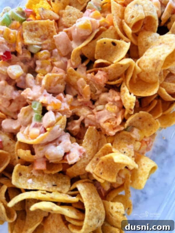 Loaded Frito Corn Salad 8 Step 4: Adding Frito chips into the chilled corn salad mixture before serving.