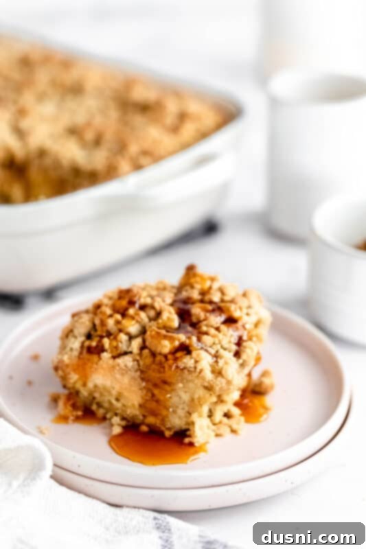 Baked French Toast Casserole with streusel topping, garnished with fresh berries and maple syrup.