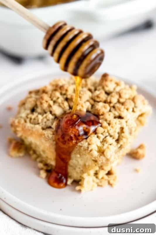 A slice of baked French toast casserole on a plate, showing the layers of bread and topping.