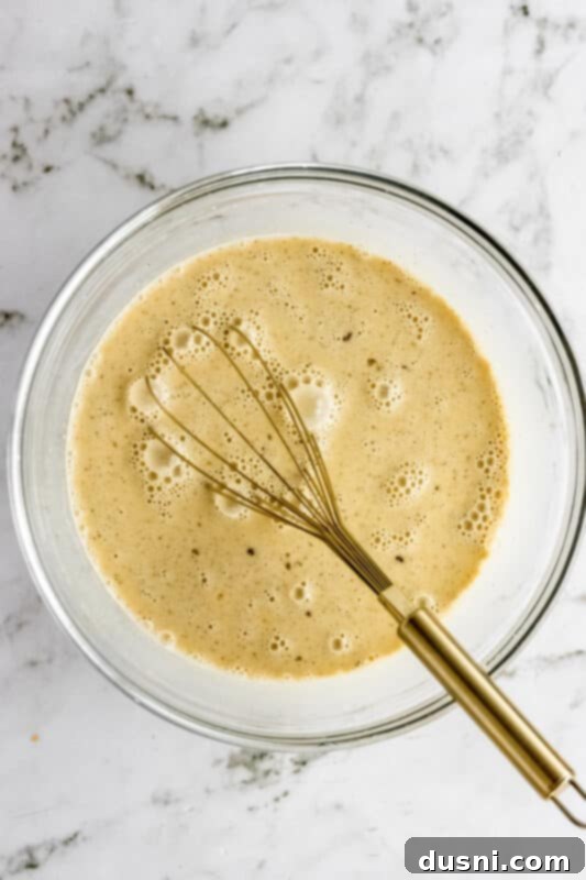 Step 2: Whisking eggs, milk, cream, and spices in a large bowl to create the custard.