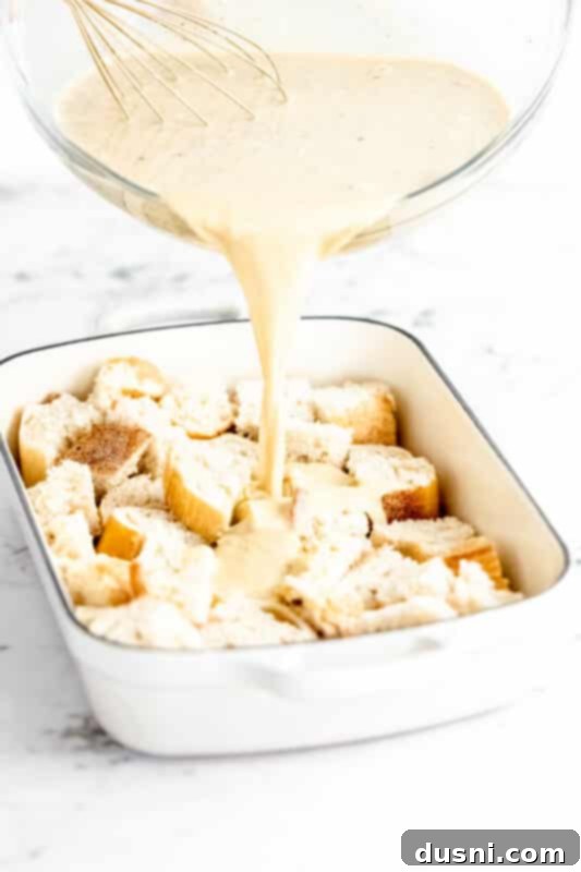 Step 3: Pouring the egg and milk mixture over the bread cubes in the casserole dish.