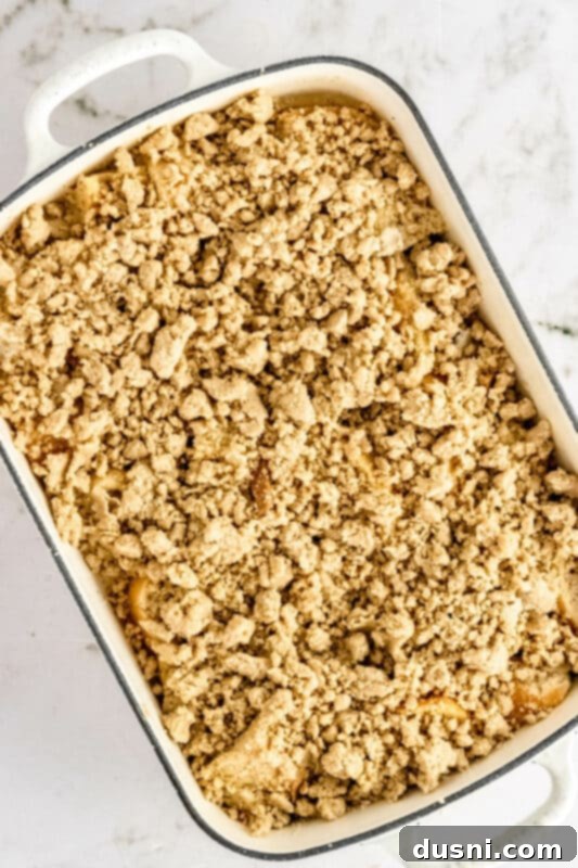 Step 5: Sprinkling the prepared streusel topping over the soaked French toast casserole.
