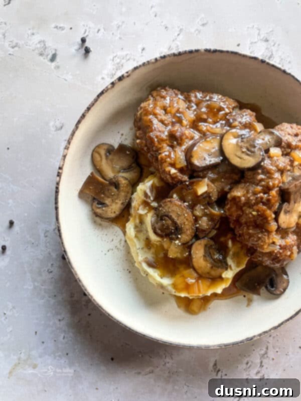 Classic Salisbury Steak with Savory Mushroom Gravy 2 Salisbury steak with mushroom gravy and mashed potatoes, garnished with parsley