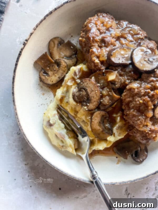 Classic Salisbury Steak with Savory Mushroom Gravy 13 Cooked Salisbury steak with mushroom gravy, ready to serve