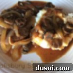 Classic Salisbury Steak with Savory Mushroom Gravy 19 overhead of salisbury steak with mushrooms and mashed potatoes on a white plate