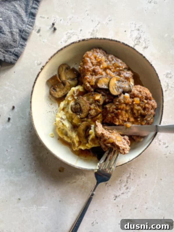 Classic Salisbury Steak with Savory Mushroom Gravy 3 Close-up of a Salisbury steak patty in rich mushroom gravy