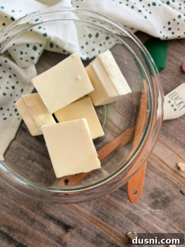 Pot of Gold Snack Blend 10 Almond bark squares and oil in a microwave-safe bowl.