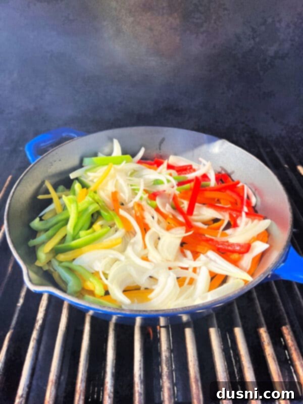 Skillet with peppers and onions on the grill