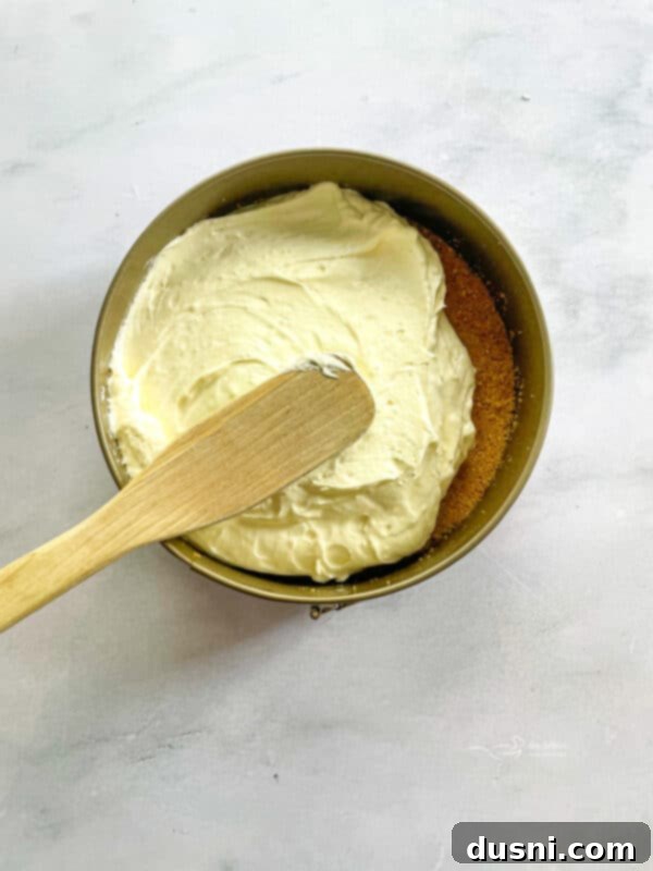 Dreamy Marshmallow Cloud Cheesecake 11 The creamy marshmallow cheesecake filling being gently folded in a bowl, showing its smooth texture.