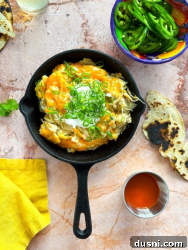 Plated serving of Slow Cooker Green Chile Chicken Enchilada Casserole with chips
