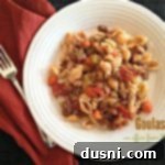 Overhead of Goulash on a white plate with a fork and a red napkin on a dark surface. Text "Goulash"