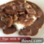 Tender Beef Tips in Rich Gravy 15 Beef Tips with Gravy over mashed potatoes on a white plate
