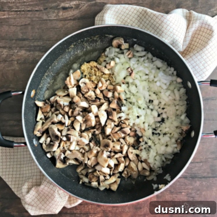 Tender Beef Tips in Rich Gravy 6 Close-up of mushrooms, onions, and garlic sautéing in butter in a skillet, key for flavor.