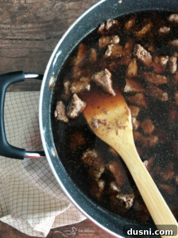 Tender Beef Tips in Rich Gravy 9 Beef tips simmering in a skillet with a rich, brown gravy, showing the sauce thickening.
