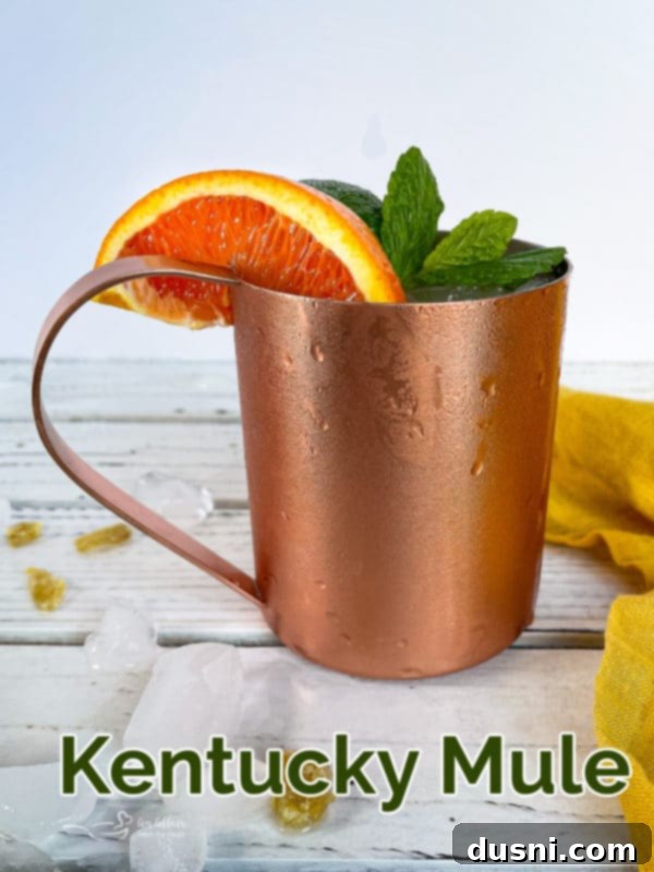 A Kentucky Mule in a copper mug with lime and mint on a wooden surface