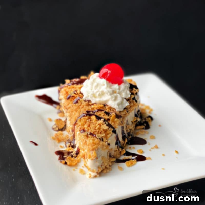 Fried Ice Cream Pie 18 A perfectly sliced piece of no-bake fried ice cream pie drizzled with chocolate syrup, showing its creamy layers and crunchy topping.