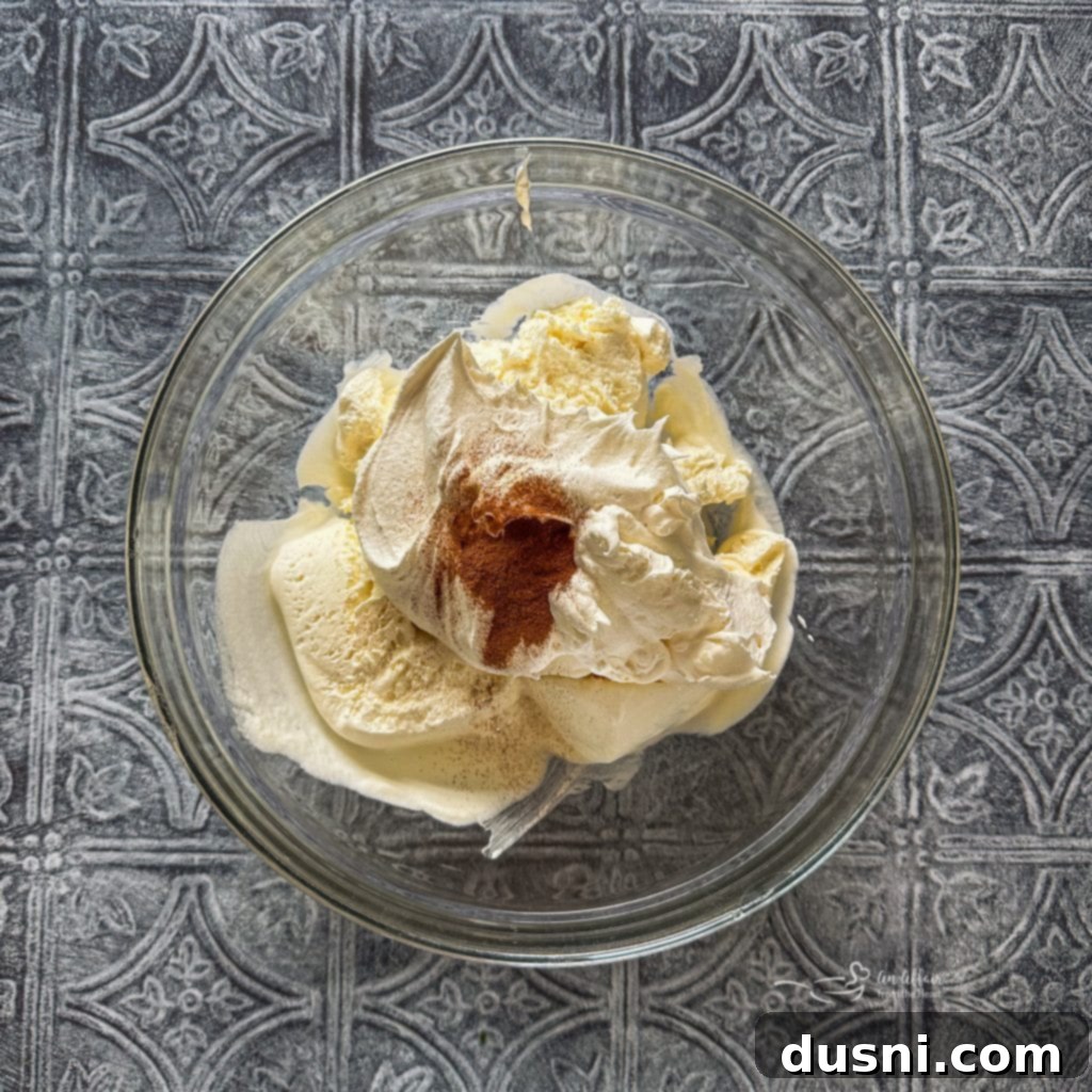 Fried Ice Cream Pie 10 Step-by-step image of folding Cool Whip and cinnamon into softened vanilla ice cream