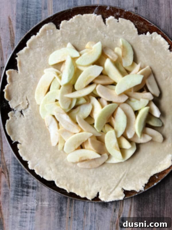 Sliced apples piled in the center of the dough