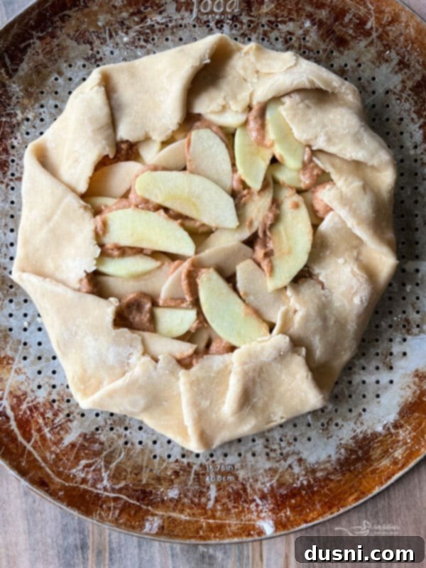 Folding the edges of the pie crust over the apple filling