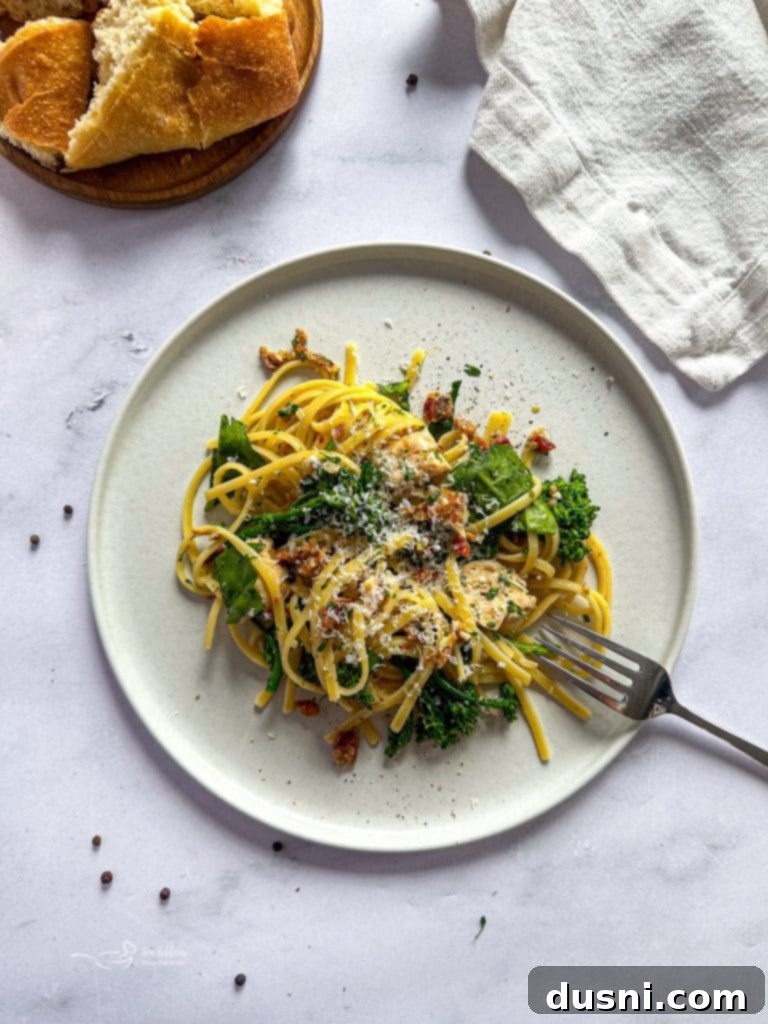 A close-up of a skillet filled with a creamy sauce, bacon pieces, and chopped shallots, ready for chicken and pasta.