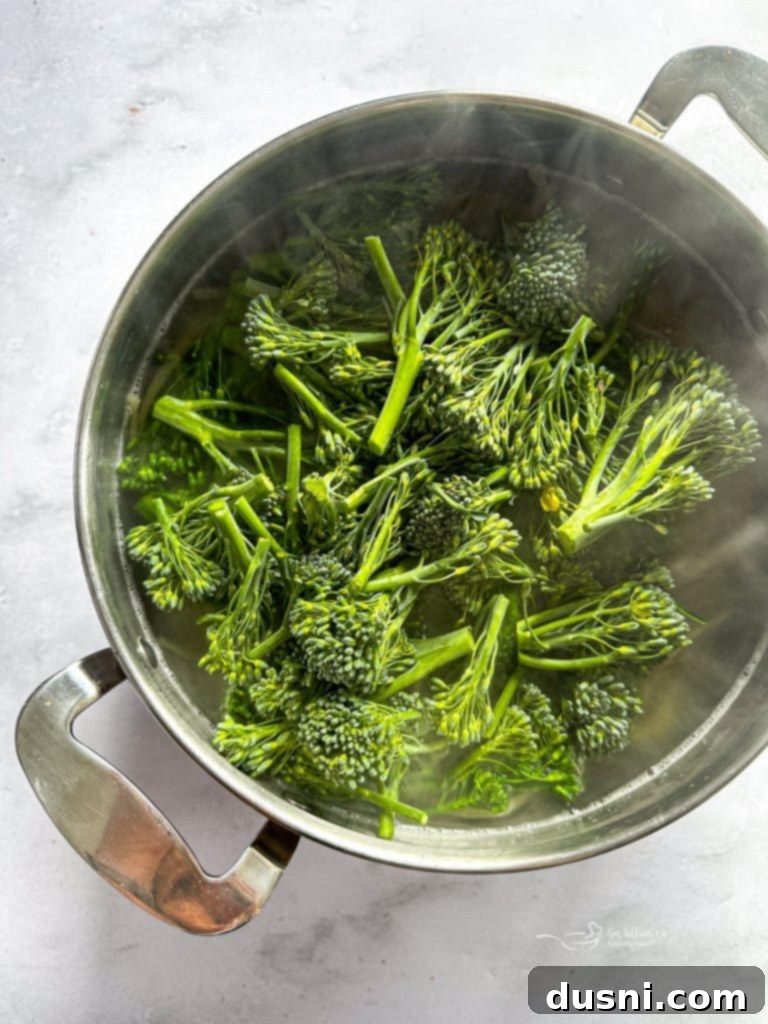 Linguine noodles and broccolini cooking in a large pot of boiling water.