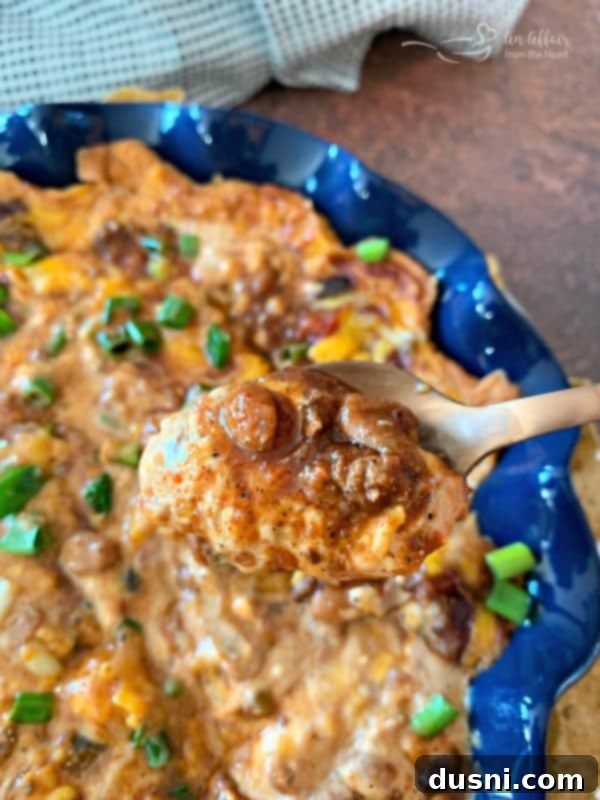 Hearty One-Pan Chili Mac 5 Baked Chili Cheese Bean Dip close up on a spoon, showcasing melted cheese and rich chili.