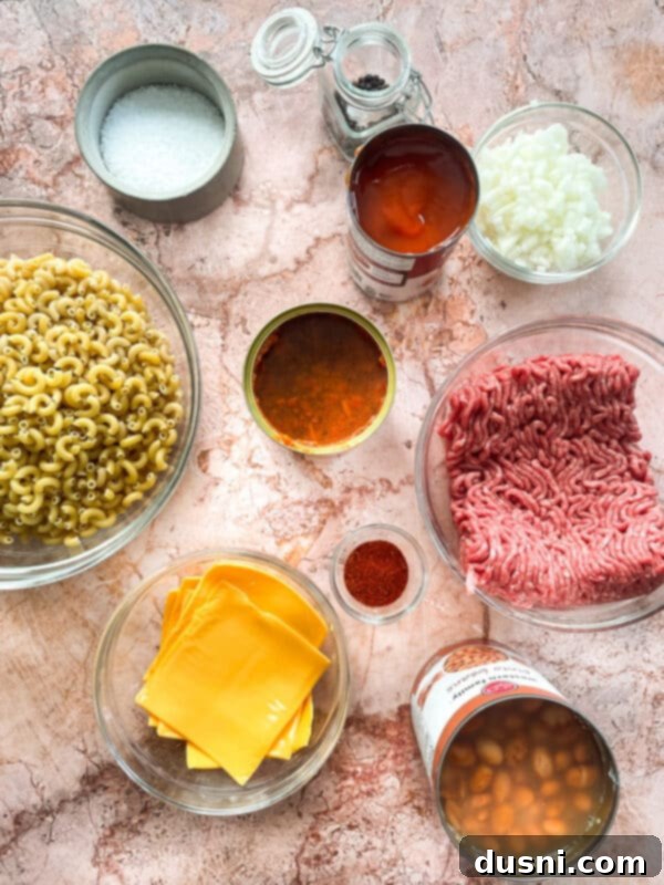 Hearty One-Pan Chili Mac 6 Ingredients laid out for Chili Mac Skillet: ground beef, onion, beans, chili, macaroni, cheese, seasoning.