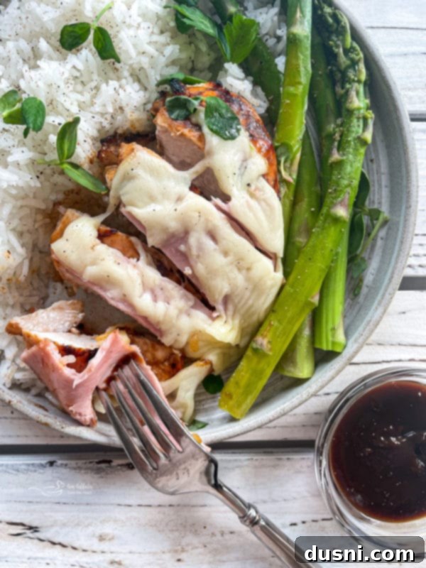 Delicious Smoky Mountain Chicken with melted cheese and fresh asparagus on the side, ready to be served for dinner