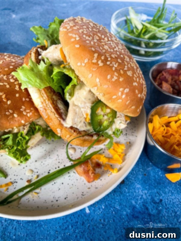 Instant Pot Crack Chicken on a sesame seeded bun, served with melted cheese and bacon