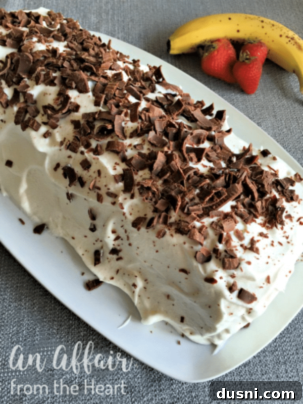 Ultimate Banana Split Jelly Roll 3 Whole Banana Split Jelly Roll Cake, uncut, on a white platter with chocolate shavings