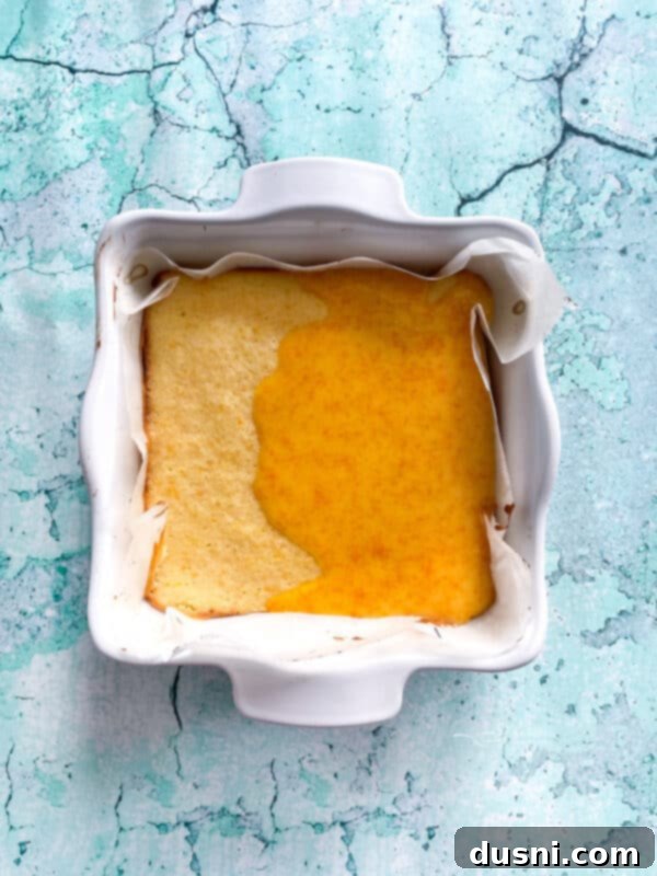 Sunshine Orange Bars 10 Pouring the orange glaze over freshly baked orange bars.