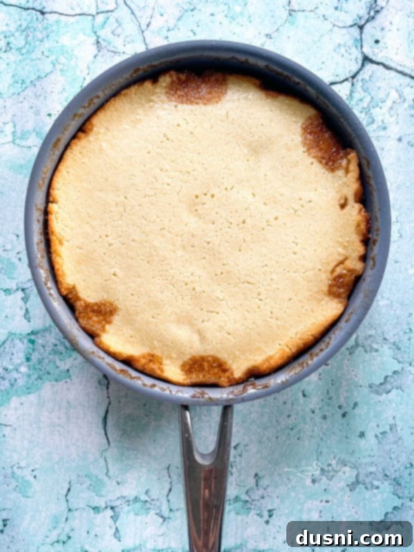 Cake batter spread over fruit in skillet
