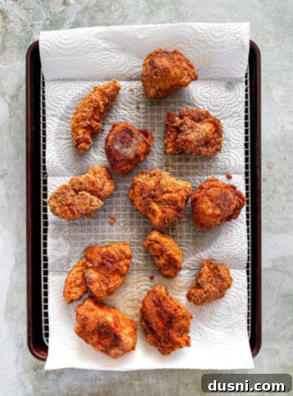 Honey-Glazed Crispy Fried Chicken 12 Cooked crispy chicken pieces draining on paper towels.