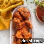 Honey-Glazed Crispy Fried Chicken 20 Close up of crispy Honey chicken on a white serving platter.