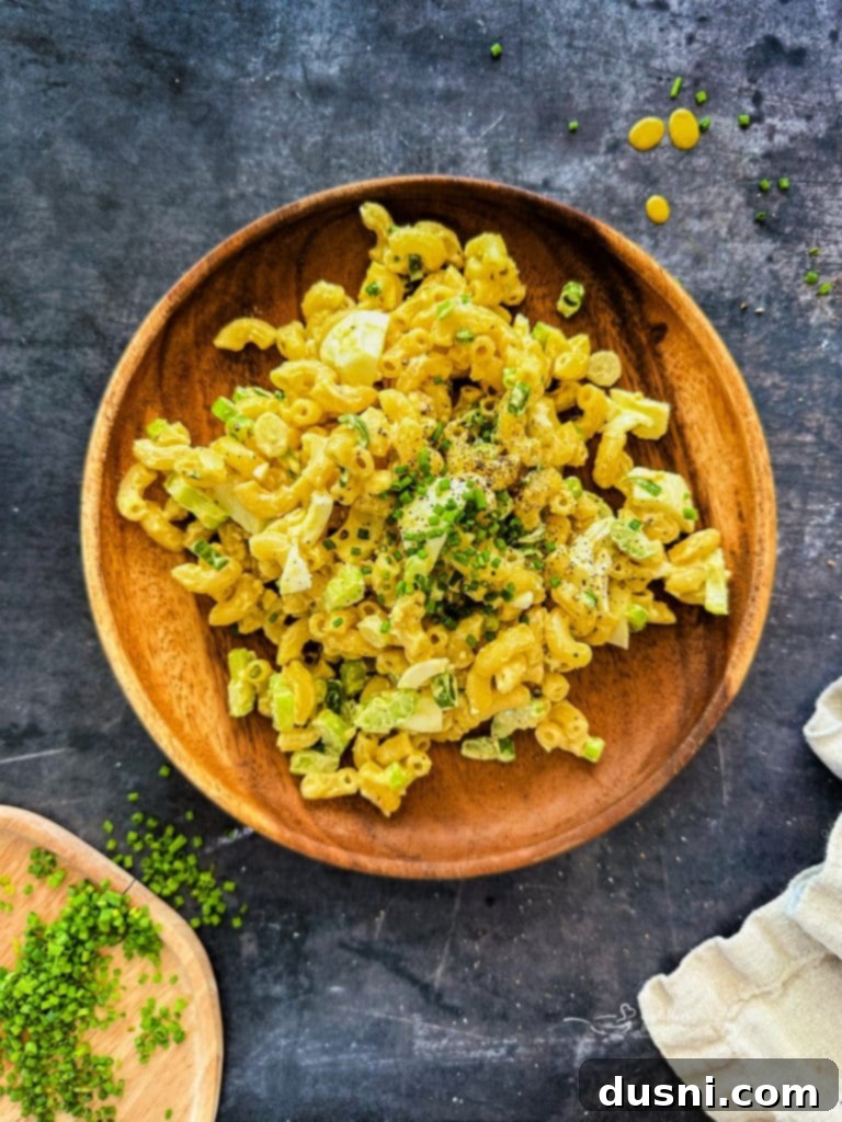 A bowl of creamy macaroni salad, garnished with fresh chives, ready to be served.