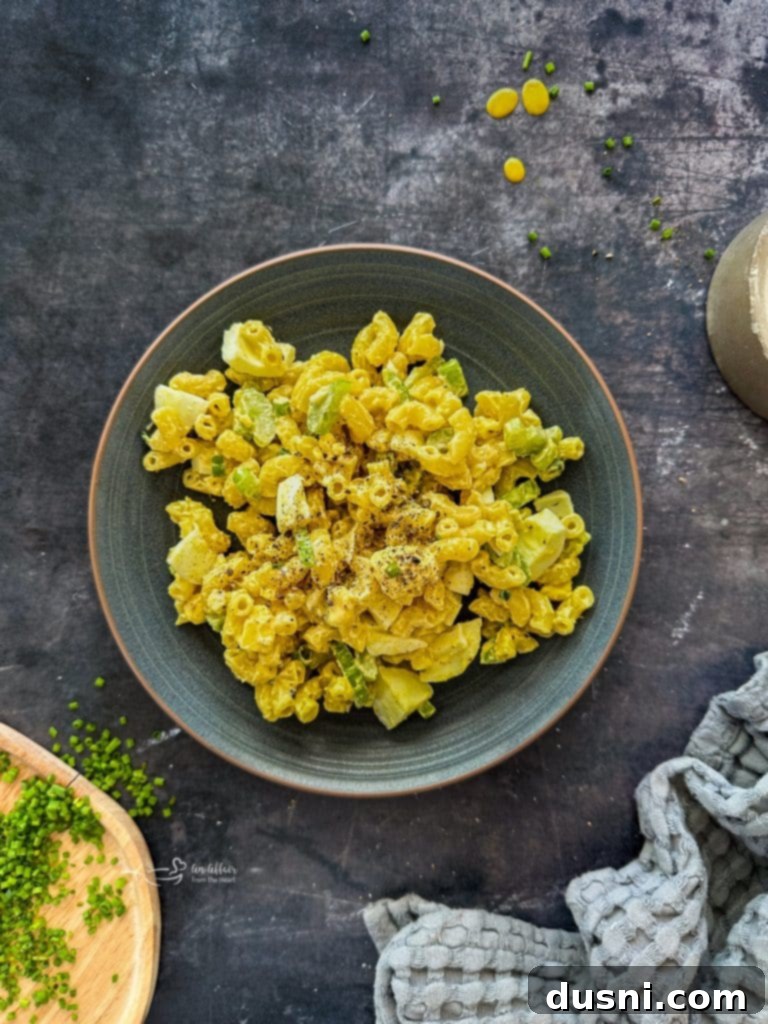 A bowl of macaroni salad with a serving spoon, ready to be enjoyed.