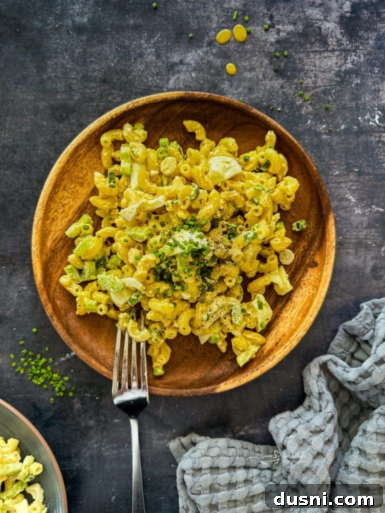Close-up of creamy macaroni salad with hard-boiled eggs and celery.